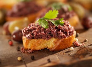 Greek Kalamata olives tapenade on a slice of bread for an aperitif